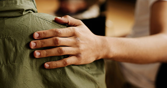 person resting their hand on someones shoulder during therapy session