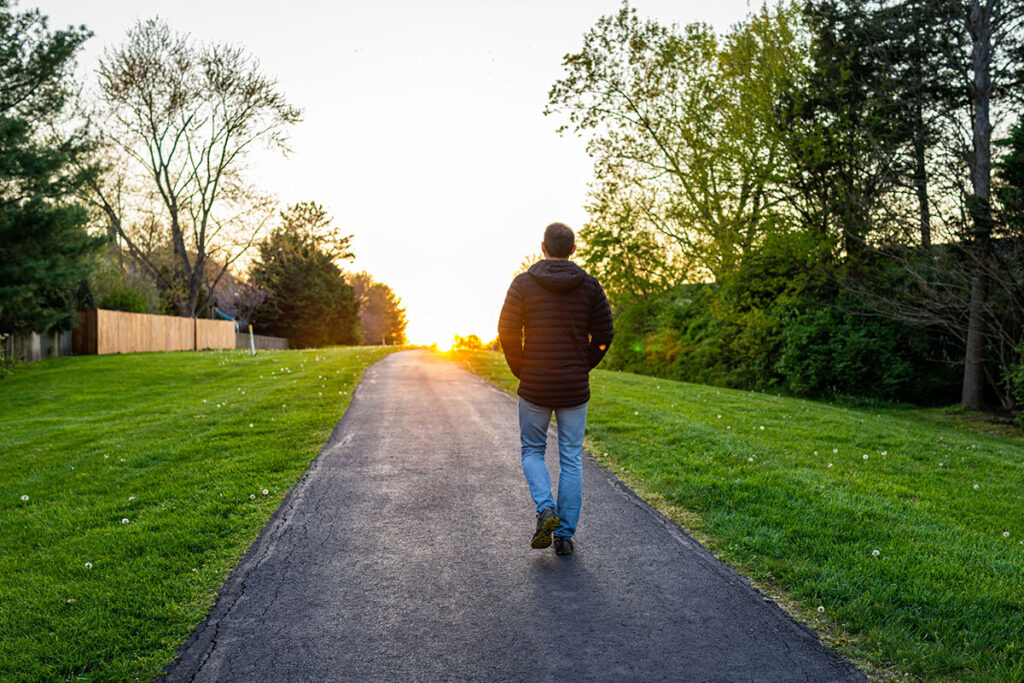 man walking down path towards a soothing light